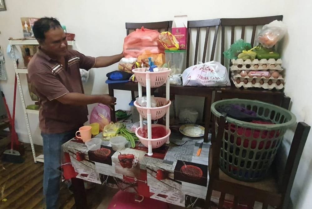 Salah seorang penduduk mula mengemas barang-barang di dalam rumah memandangkan air mulai masuk ke dalam rumah susulan hujan lebat berterusan.