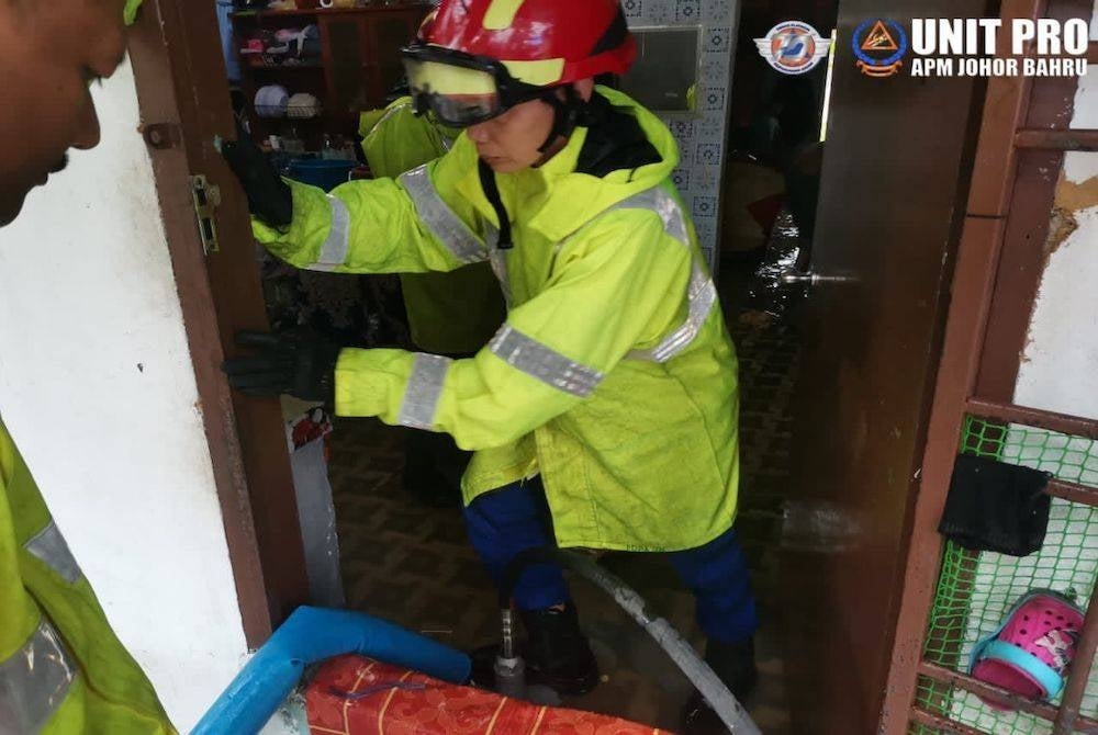 Anggota APM membantu membersihkan rumah penduduk yang terjejas akibat banjir kilat pada Sabtu.