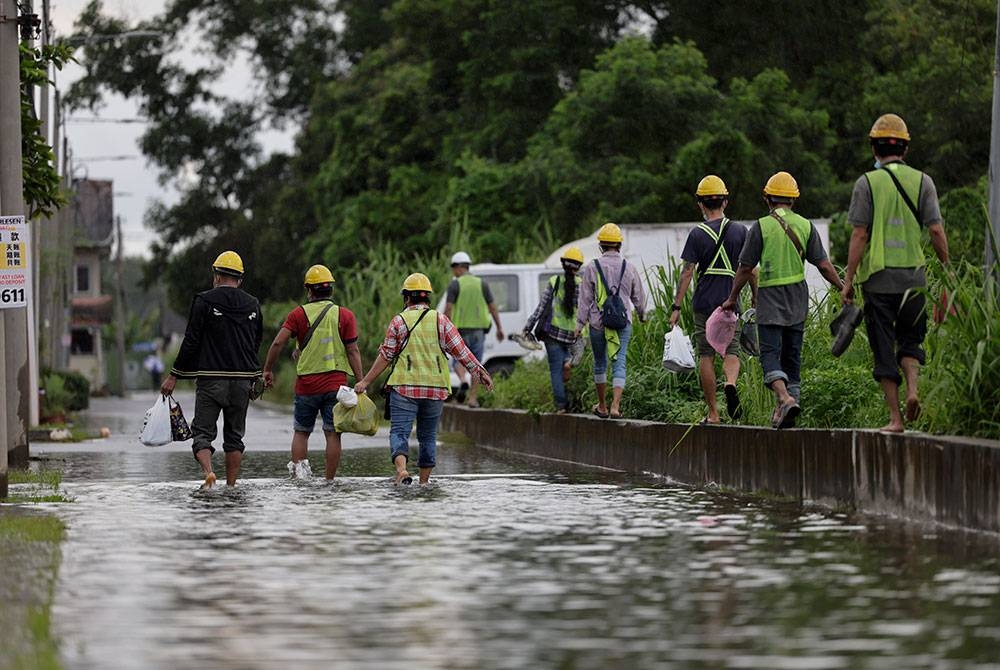 Beberapa pekerja meredah banjir di sebuah jalan ketika tinjauan di sekitar Klang, hari ini.