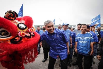 Ahmad Zahid beramah mesra dengan masyarakat Cina pada perjumpaan bersama komuniti itu sempena PRU15 di Batu 12, Hutan Melintang. - Foto Bernama