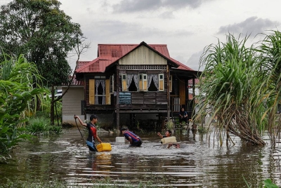 Kanak-kanak bermain air di perkarangan sebuah rumah yang dilanda banjir ketika tinjauan di sekitar Klang, hari ini.