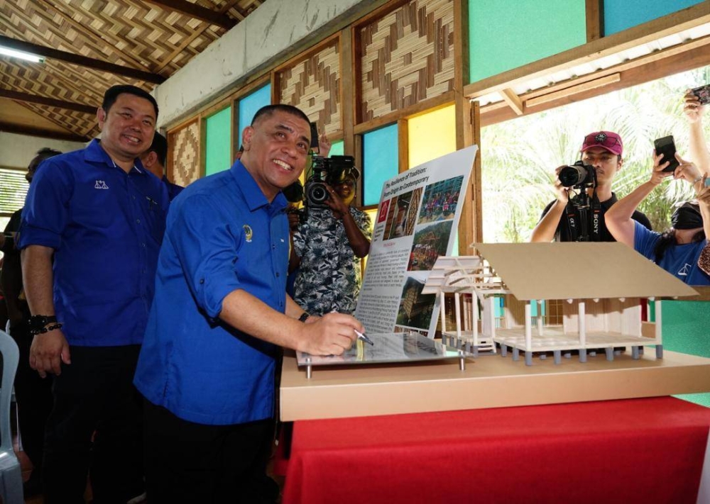 Saarani menandatangani plak simbolik merasmikan Balai Desa Semai Kampung Orang Asli Sungai Lah, Chenderiang, Tapah pada Ahad. 