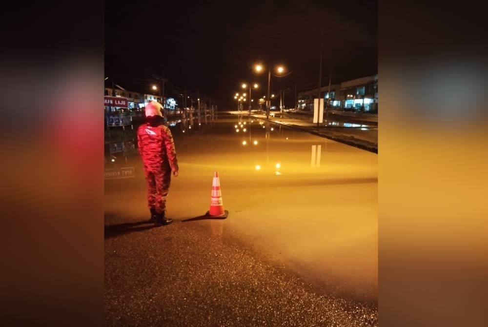 Anggota bomba memantau keadaan banjir di Sungai Siput. - Foto JBPM