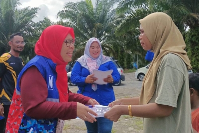 Jamilah (kiri) menyantuni pengundi di Permatang Raja sempena program ziarah kasih.