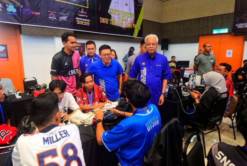 Ismail Sabri (kanan) bermesra bersama pemain e-sukan yang berentap dalam acara tersebut pada Karnival #KeluargaMalaysia: Anak Muda GEGOR Bera.