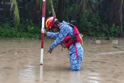 Anggota APM Kubang Pasu memeriksa paras air di kawasan perumahan di Sintok dan Jalan UUM pada Isnin. - Foto APM