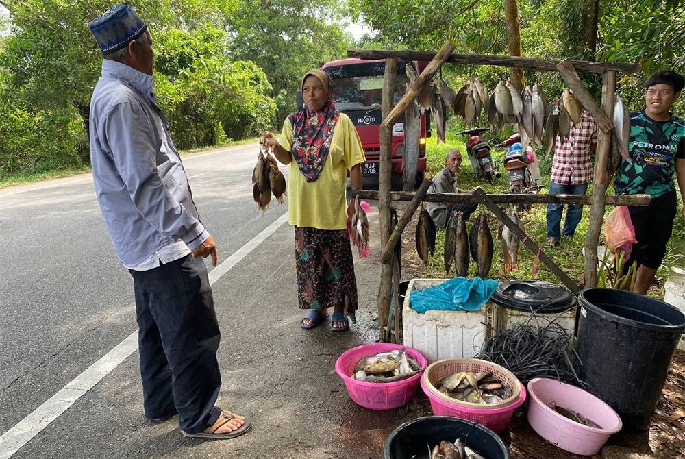 Faridah (dua dari kiri) melayan pelanggan yang datang ke gerainya di Kalbot Lima, Rantau Panjang untuk mendapatkan bekalan ikan darat.