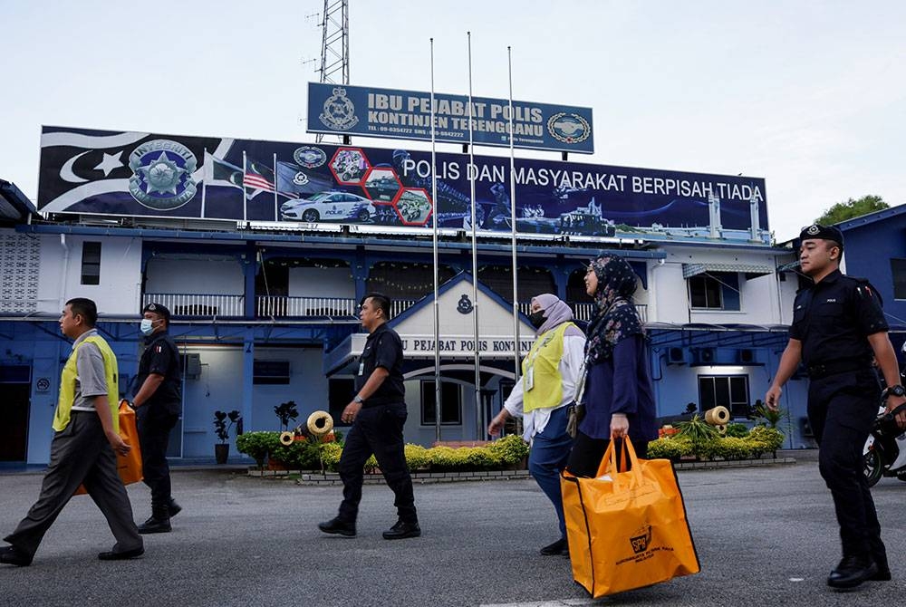 Anggota Polis Diraja Malaysia (PDRM) mengiringi petugas Suruhanjaya Pilihan Raya (SPR) yang membawa keluar kertas undi dari balai polis untuk ke tempat pengundian bagi proses mengundi awal bagi PRU15 di Ibu Pejabat Polis Kontinjen Terengganu hari ini.