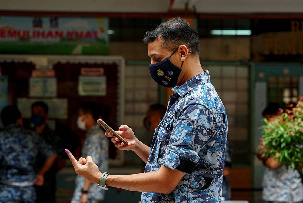 Seorang anggota Tentera Udara Diraja Malaysia (TUDM) dilihat mengambil gambar jarinya yang telah dicelup dakwat biru selepas selesai mengundi awal sempena Pilihan Raya Umum ke-15 (PRU15) di Sekolah Kebangsaan Desa Tun Hussein Onn hari ini.