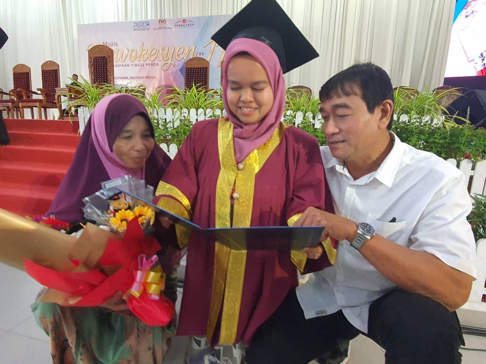 Nurul Izzah menunjukkan sijil yang diterima kepada ibu bapanya Mohd Asri Abdul Rahman (kanan) dan Hasmah Hassan (kiri).