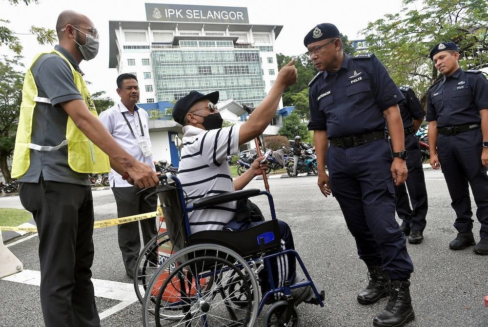 Ketua Polis Selangor, Datuk Arjunaidi Mohamed (dua dari kanan) beramah mesra bersama pesara polis Sarjan Azmi Abdul Rani yang berkerusi roda selepas menjalankan tanggungjawab mengundi awal sempena Pilihan Raya Umum ke-15 (PRU15) di Dewan Utama Ibu Pejabat Polis Kontinjen Selangor, pada Selasa. - Foto Bernama