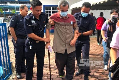 Che Mustapa (tiga dari kiri) dipapah anggota-anggota ketika hadir untuk membuang undi di pekarangan Taska IPK Kelantan, Kota Bharu.