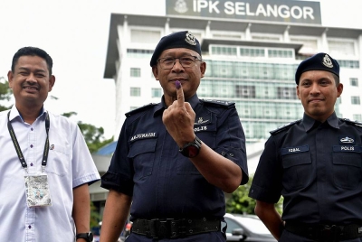 Arjunaidi (tengah) menunjukkan jarinya selepas menjalankan tanggungjawab mengundi awal sempena Pilihan Raya Umum ke-15 (PRU15) di Dewan Utama Ibu Pejabat Polis Kontinjen Selangor, pada Selasa. Turut mengiringi Ketua Polis Daerah Shah Alam, Asisten Komisioner Mohd Iqbal Ibrahim (kanan). - Foto Bernama
