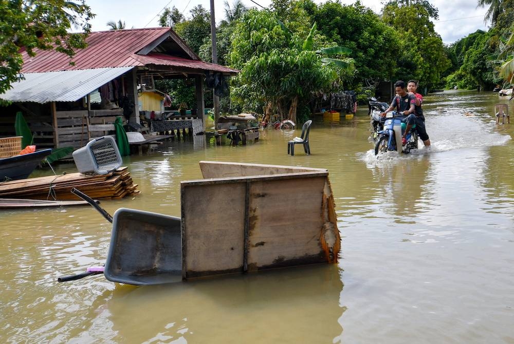 Penduduk meredah banjir menggunakan motosikal ketika tinjauan di Kampung Tersang, Rantau Panjang pada Isnin. - Foto Bernama