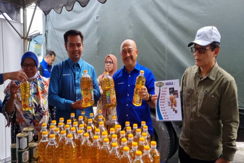 Abd Rahman (dua dari kanan) memegang botol minyak masak yang dijual pada Jualan Murah Keluarga Peladang di Kampung Nelayan Sungai Besar di sini pada Khamis.
