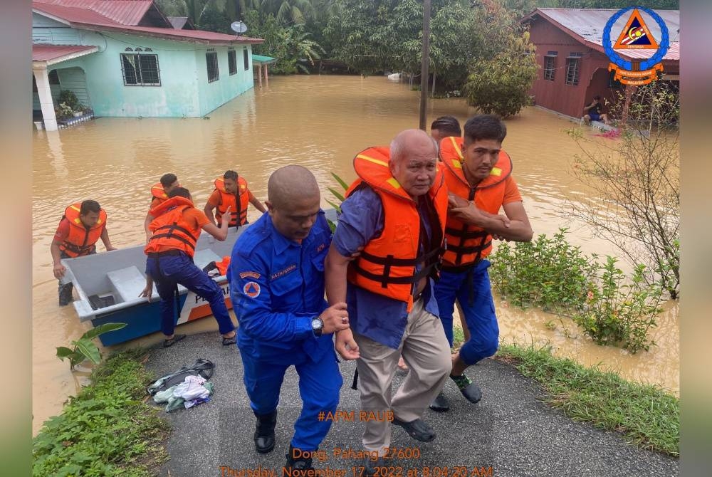 Anggota APM membantu memindahkan seorang warga emas dari Kampung Gali Tengah ke PPS selepas kampung itu dilanda banjir pada Khamis. - Foto APM