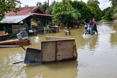 Penduduk meredah banjir menggunakan motosikal ketika tinjauan di Kampung Tersang, Rantau Panjang pada Isnin. - Foto Bernama