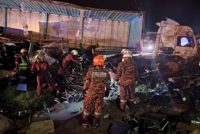 Pasukan bomba menjalankan operasi mengeluarkan mayat mangsa yang terperosok di balik muatan timbunan besi. - Foto ihsan pembaca