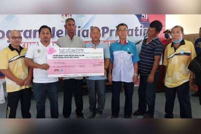 Ahmad Aizuddin (dua dari kiri) menyerahkan replika cek kepada ahli Persatuan Nelayan Matang pada Program Jelajah Prihatin LKIM Bersama Nelayan Sungai Matang di Matang pada Jumaat.