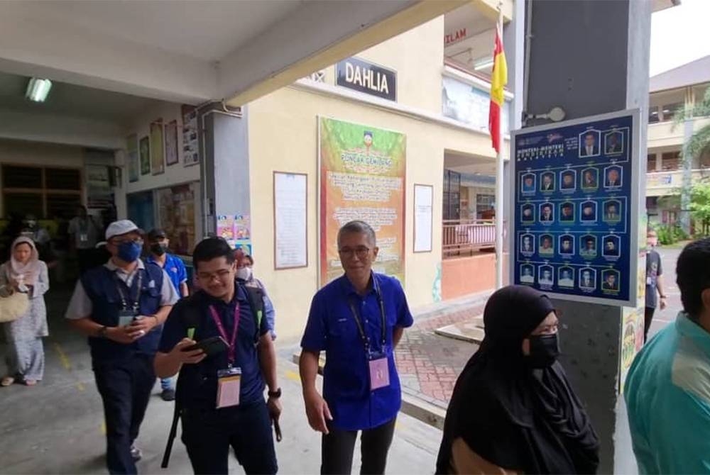 Tengku Zafrul (tiga dari kanan) beratur bersama pengundi lain di SK Puncak Alam di sini pada Sabtu.