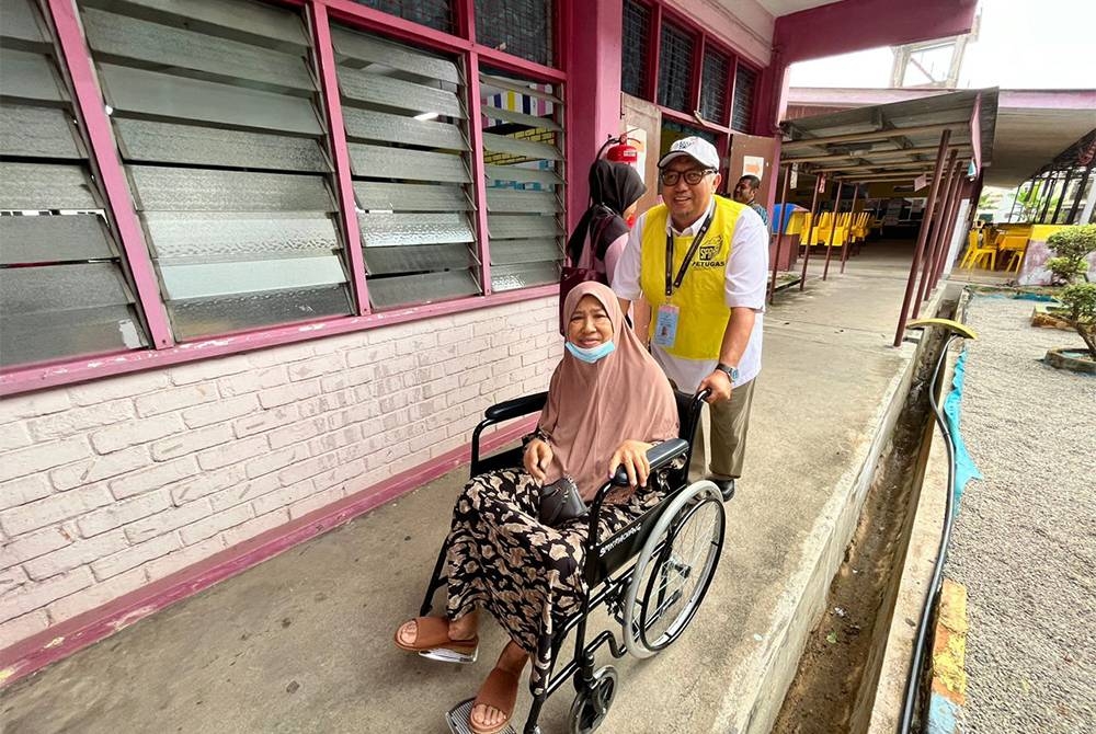 Nora ditolak menggunakan kerusi roda oleh petugas SPR selepas selesai membuang undi di SMK Machang, di sini.