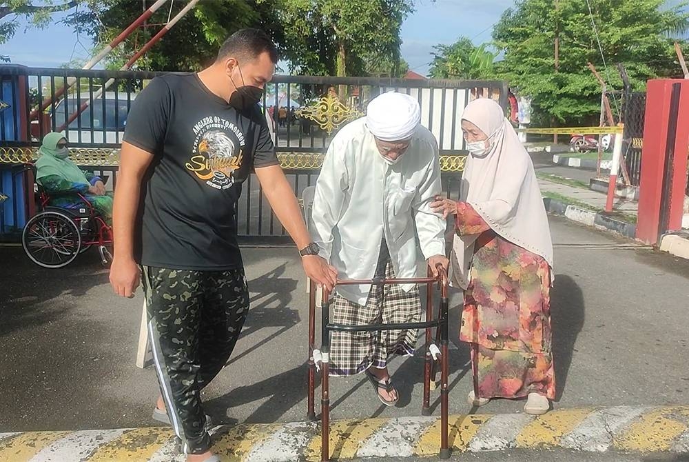 Mohd Akmal menemani datuknya, Mohd Jelani Mat Akhir dan neneknya, Siti Aishah Ahmad membuang undi di Kolej Tingkatan Enam Sultan Sallehuddin, di sini, pada Sabtu.