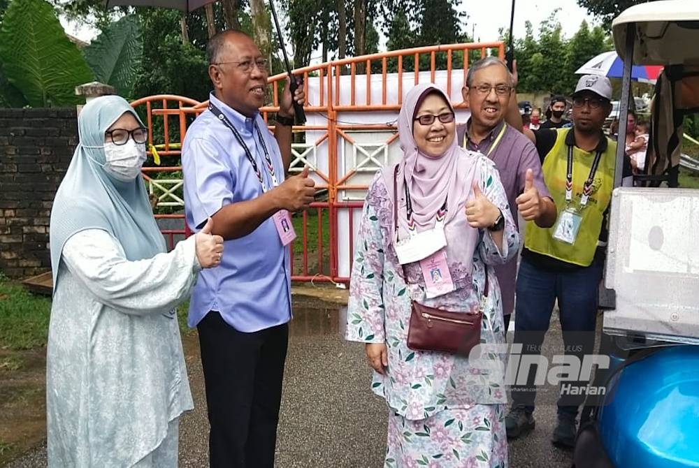 Fuziah (tiga dari kanan) dan Abdul Hamid (dua dari kiri) sempat bergambar setelah bertembung di pintu masuk pusat mengundi di SMK Tok Sira pada Sabtu.
