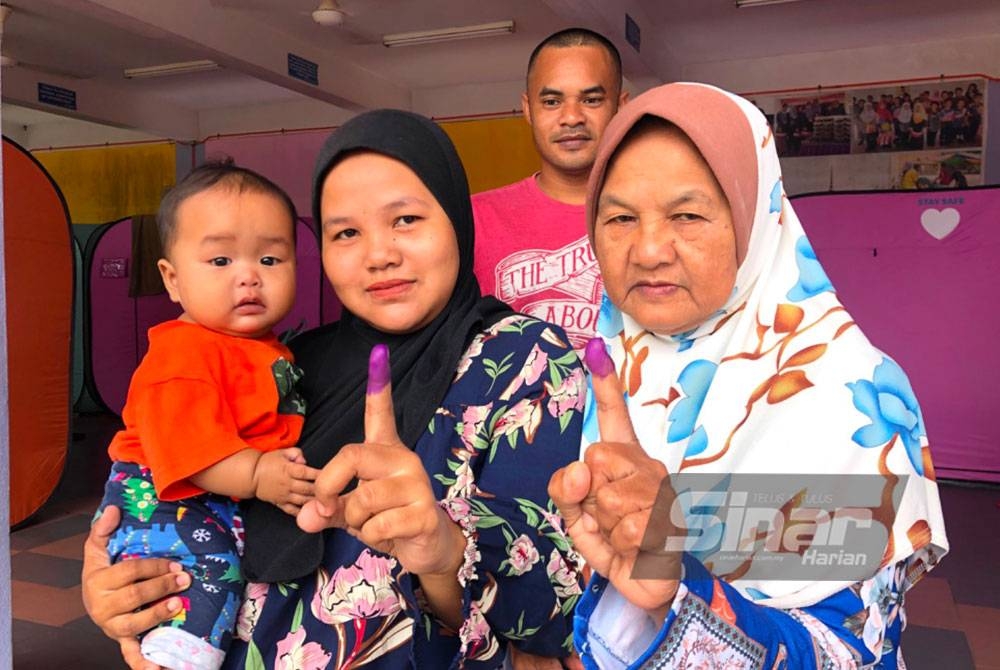 Rashina Iliayana dan Kamariah menunjukkan jari berdakwat selepas selesai mengundi pada PRU15.