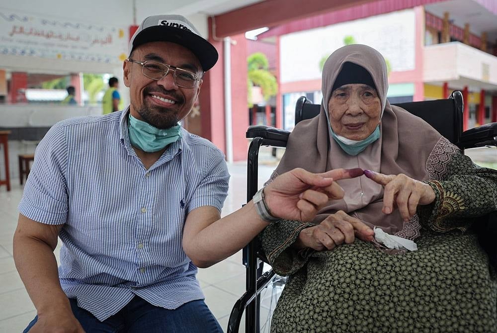Radzi bersama ibu saudaranya Meriam Abd Rahman, 83 menunjukkan jari sebagai tanda selesai melaksanakan tanggungjawab sebagai pengundi pada PRU15 di SMK Sri Muar hari ini. - Foto Bernama.