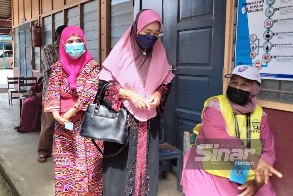 Zauyah (kiri) tiba di Pusat Mengundi SK Padang Mandol bersama ibunya.