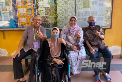 Fuziah bersama suami, ibu dan bapa saudara menunjukkan jari dengan kesan dakwat selepas selesai mengundi di pusat mengundi di SMK Tok Sira pada Sabtu.