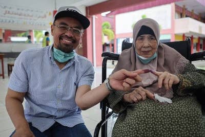 Radzi bersama ibu saudaranya Meriam Abd Rahman, 83 menunjukkan jari sebagai tanda selesai melaksanakan tanggungjawab sebagai pengundi pada PRU15 di SMK Sri Muar hari ini. - Foto Bernama.