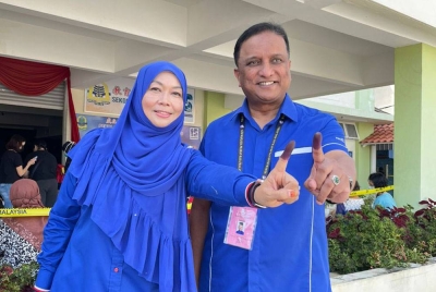 Reezal dan Ismalina menunjukkan jari mereka yang telah bertanda selepas membuang undi di SJKC Pei Yu di Kepala Batas pada Sabtu.