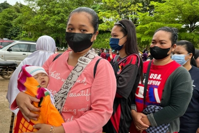 Pengundi muda warga Orang Asli Cerrioy Anuar, 21, memangku bayi lelaki Biblee Amiru Irman yang berusia tiga bulan, bersemangat beratur seawal 8 pagi tadi untuk mengundi Sekolah Kebangsaan Kuala Betis bagi Parlimen Gua Musang hari ini. - Foto Bernama.