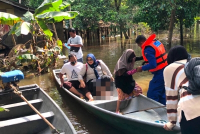 Jah (tiga dari kanan) dibantu untuk keluar dari bot yang dinaiki mangsa banjir itu.