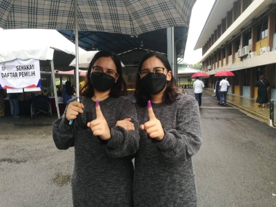 Dayini Zulqamaria Zulkifli dan Dayana Zulqamarina menunjukkan jari masing-masing selepas selesai mengundi di SK Taman Rinting 1, Pasir Gudang, pada Sabtu.