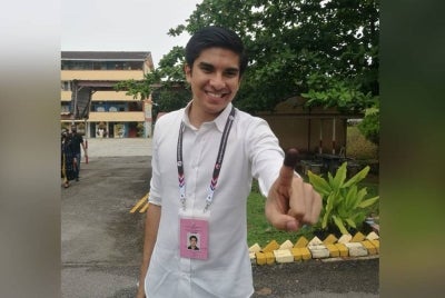 Syed Saddiq menunjukkan jarinya yang telah dicelup dakwat setelh selesai membuang undi pada Sabtu.