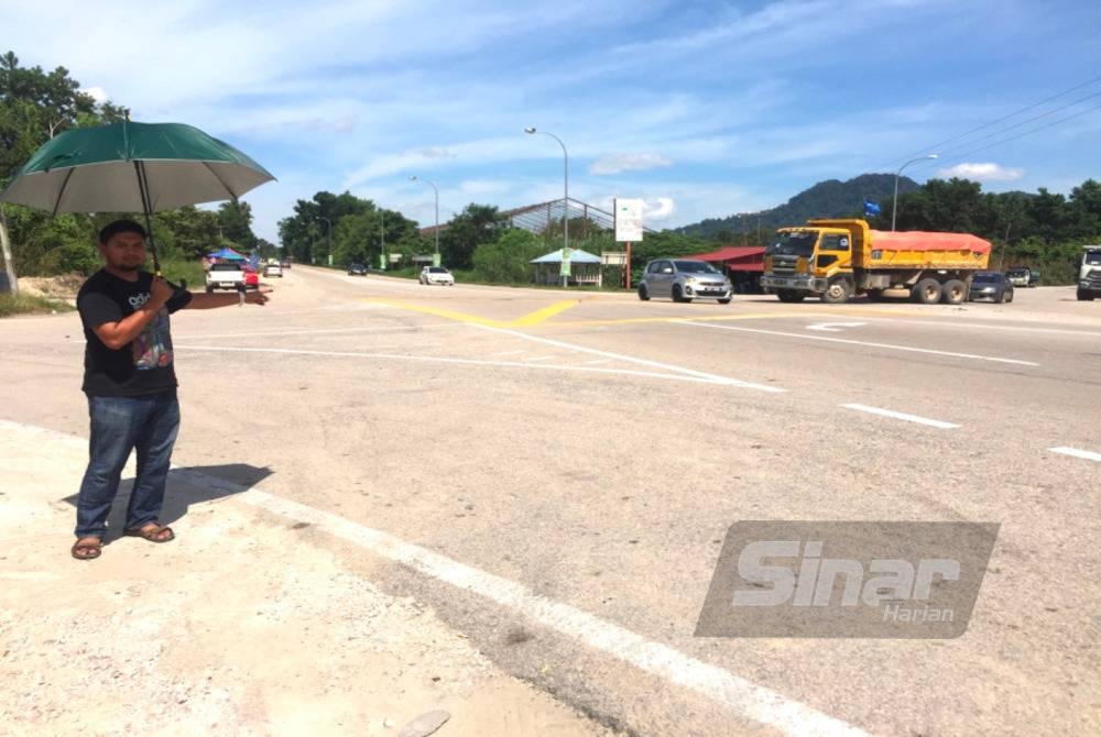 Muhd Sadiqi (kiri) menunjukkan keadaan di persimpangan Kuari Bukit Buloh, Machang.
