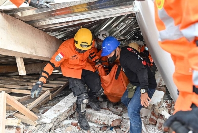 Anggota penyelamat membawa keluar mayat yang terperangkap bawah runtuhan rumah di Cianjur. - AFP