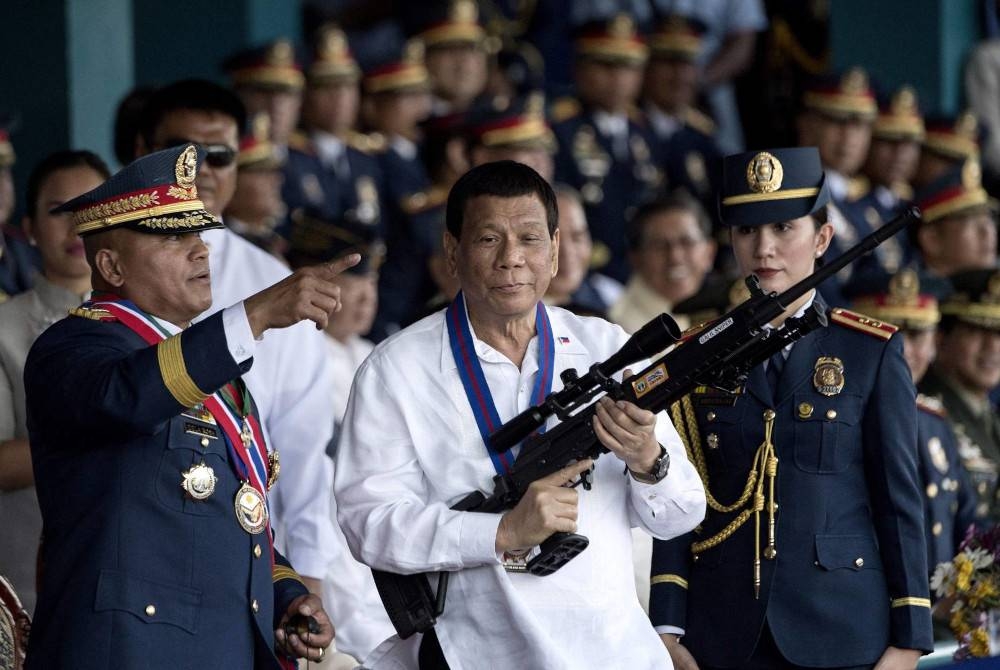 Le président philippin Rodrigo Duterte (au centre) tient un fusil de sniper après avoir déclaré la guerre aux trafiquants de drogue.  - Agence photo
