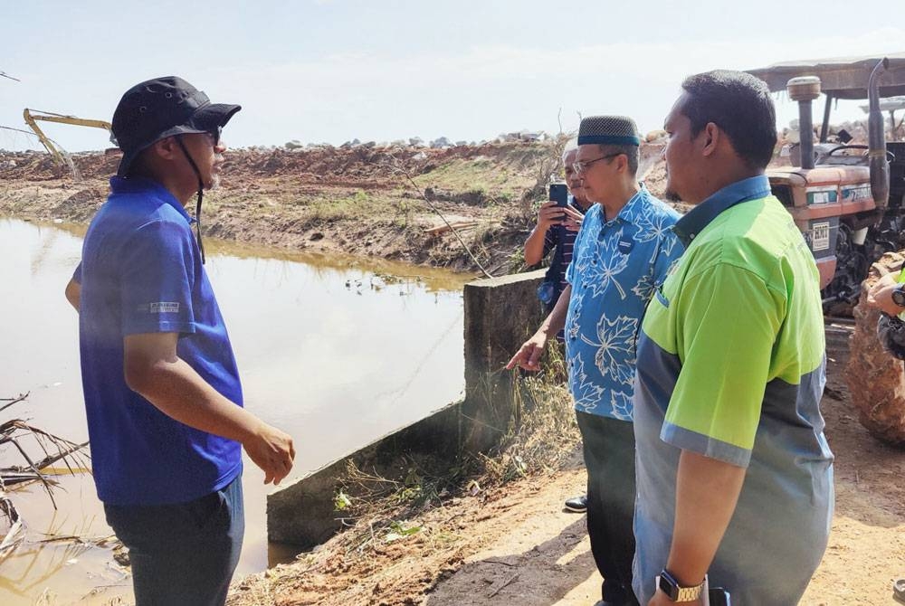 Zulkafperi (deuxième à droite) inspecte jeudi l'état des pneus en cours de réparation sur la côte de Kampung Sungai Kajang.