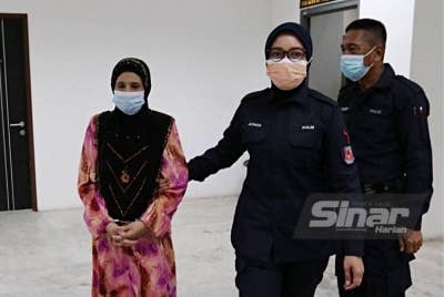 Soe Soe (kiri) dikawal polis ketika dibawa keluar lokap menuju ke bilik Mahkamah Tinggi Kota Bharu.