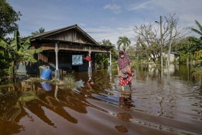 Seorang wanita mengharungi air yang mulai surut di Kampung Johan Setia, Klang ketika tinjauan bencana banjir yang melanda beberapa kawasan di Selangor pada 17 November lalu. - Foto Bernama