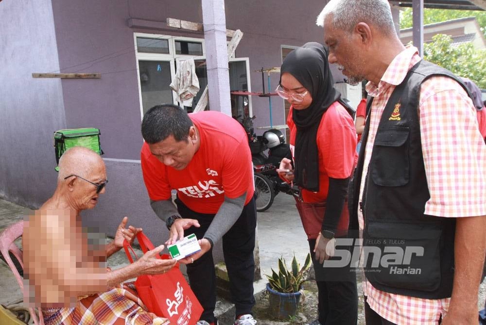 Nik Justin menyerahkan Kit Bantuan Bencana Sinar Karangkraf kepada salah seorang penerima warga emas, Salleh Mat, 87.