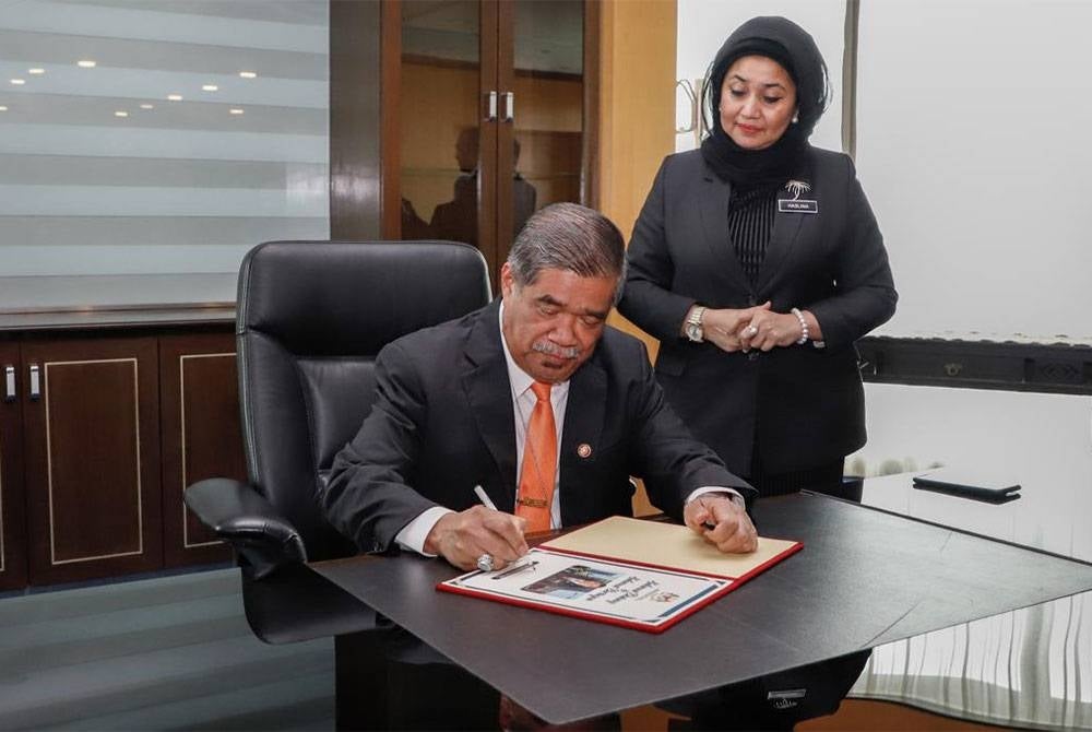 Mohamad menandatangani buku sebagai simbolik memulakan tugas sebagai Menteri Pertanian dan Keterjaminan Makanan sambil diperhatikan Ketua Setiausaha Kementerian, Datuk Haslina Abdul Hamid.