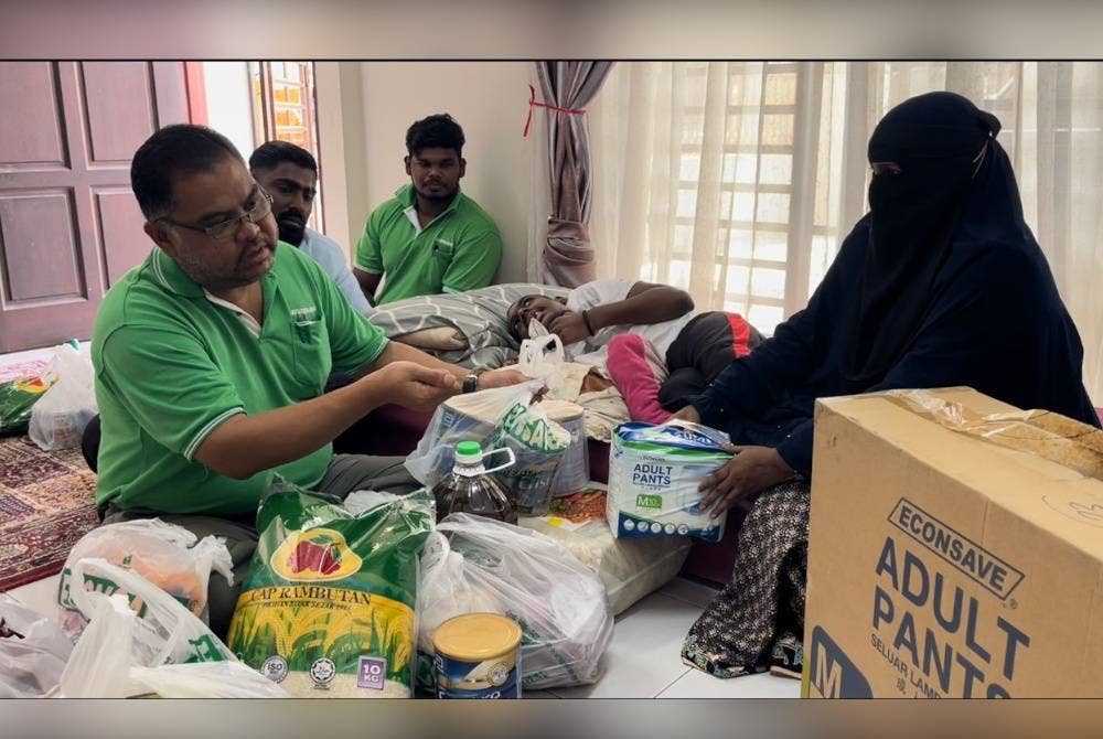 Mas Imran menyerahkan sumbangan kepada Rahimah (kanan) di Taman Seri Austin, Johor Bahru pada Isnin.