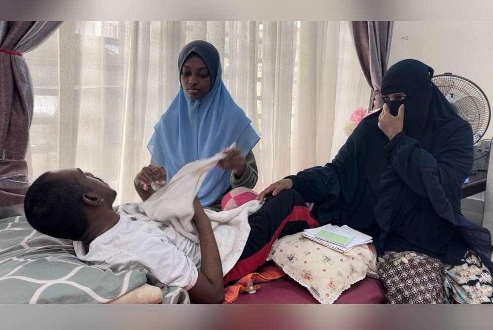 Rahimah (kanan) menguruskan keperluan Muhammad Nihal yang terlantar di Taman Seri Austin, Johor Bahru.