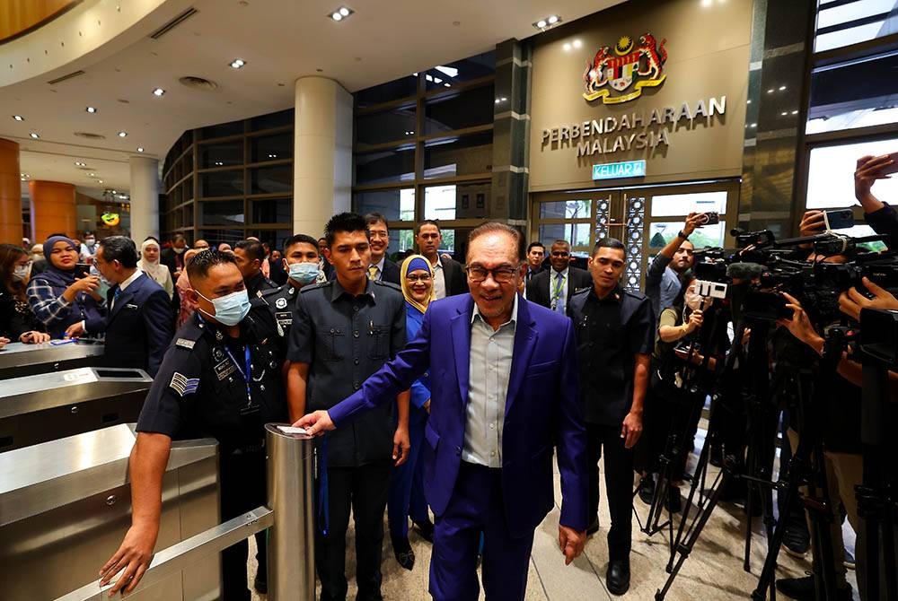 Anwar (tengah) mengimbas kad akses sejurus tiba bagi memulakan tugas secara rasmi sebagai Menteri Kewangan di Kementerian Kewangan, pada Selasa. - Foto Bernama
