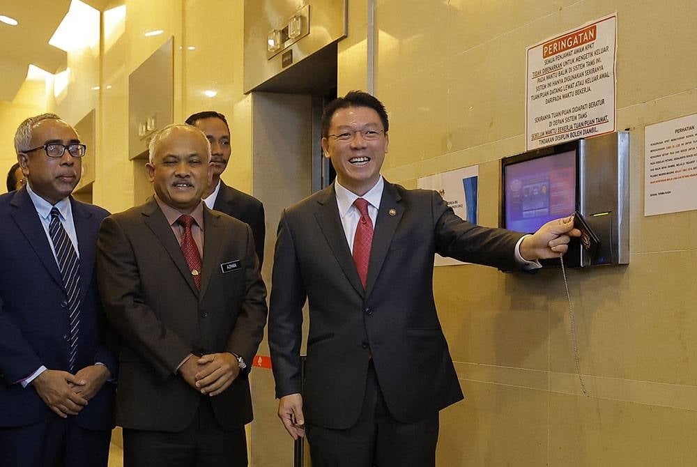 Kor Ming mengimbas kad perakam waktu semasa hadir untuk memulakan tugas pada Selasa. - Foto Bernama