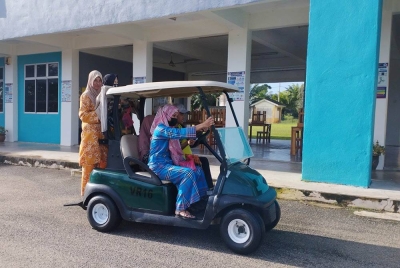 Pengundi menaik buggy untuk ke saluran mengundi di SMK Tanjung Gemuk pada Rabu.